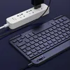 A black keyboard is shown connected to a white power strip with a black adapter plugged in. Náhled obrázku produktu