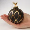 A hand holding a black and gold Christmas ornament. Podgląd zdjęcia produktu
