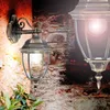 Two outdoor wall lamps are mounted on a stone wall, with a plant in the foreground. Voir les images du produit