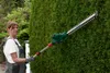 A woman is trimming a hedge with a telescopic hedge trimmer. Produktbild-Vorschau