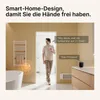 A man is walking through a doorway in a bathroom, holding a smart device, and interacting with a smart speaker. A towel rack is visible on the left. Produktbild-Vorschau