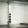A close-up view of a stainless steel power strip with four outlets mounted on a kitchen backsplash. Produktbild-Vorschau