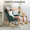 A woman is relaxing in a dark green rocking chair in a living room setting. Anteprima dell’immagine prodotto