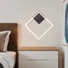 A modern bedroom scene with a bedside table and a diamond-shaped wall lamp. Voir les images du produit