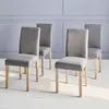 Four gray upholstered dining chairs with light wood legs are arranged on a white floor in front of a light gray paneled wall. Produktbild-Vorschau