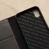 A close-up view of the interior of a black leather iPhone case, showing embossed branding. Produktbild-Vorschau
