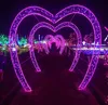 A pathway lined with illuminated heart-shaped arches at night. Produktbild-Vorschau