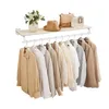 A wall-mounted shelf with a clothing rack below, displaying several neutral-toned shirts and jackets. Produktbild-Vorschau