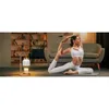 A woman is doing yoga in a living room with a candle warmer lamp in the foreground. Náhled obrázku produktu