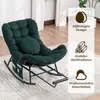 A green rocking chair with a round pillow and side pockets, placed on a rug in a room with white curtains and wooden flooring. Produktbild-Vorschau