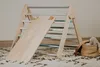 A wooden climbing triangle with a slide, placed on a rug. Voir les images du produit