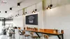 A cafe or restaurant interior with a long wooden counter and stools, featuring a chalkboard menu. Podgląd zdjęcia produktu