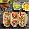 A top-down view of three shrimp tacos with various toppings, served with lime wedges and corn kernels on a wooden table. Produktbild-Vorschau