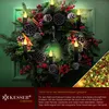 A Christmas wreath decorated with pine cones, berries, cinnamon sticks, and LED candles, mounted on a green door. Produktbild-Vorschau