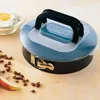 A Kaiser springform pan with a lid and handle, placed on a wooden surface with some baking ingredients like flour, egg, and raisins scattered around. Produktbild-Vorschau
