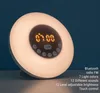 A digital alarm clock with a simulated sunrise and various features displayed on a table against a dark blue background. Produktbild-Vorschau