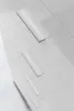 A close-up, angled view of a white sideboard with three silver drawer pulls. Voir les images du produit