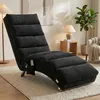 A dark gray chaise lounge is shown in a living room setting, with a lamp, plant, and artwork in the background. Produktbild-Vorschau