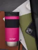 A pink Contigo travel mug is placed next to a laptop, a green notebook, and a smartphone, suggesting a work or study environment. Anteprima dell’immagine prodotto