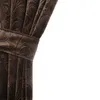 A close-up of a brown velvet curtain with an embossed floral pattern, tied back with a fabric band. Podgląd zdjęcia produktu