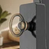 A close-up of a decorative ring pull on a black surface, with a blurred background of a room. Náhled obrázku produktu