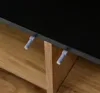 A close-up view of a sideboard's edge, showing two small gray push-to-open latches attached to the underside of a black surface, with wooden shelves visible below. Anteprima dell’immagine prodotto