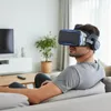 A man is using a VR headset while sitting on a couch in a living room. Produktbild-Vorschau