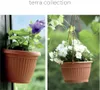 A collage of two images showing terracotta-colored planters with plants. The left image shows a planter attached to a wooden surface with a purple flower. The right image shows a hanging planter with white flowers. Náhled obrázku produktu