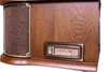 A close-up view of the side of a vintage-style stereo system, focusing on a speaker grille and an 'AUTO STOP' control panel. Produktbild-Vorschau