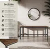 A console table with a dark wood top and black metal legs is shown in a modern interior setting with a round mirror and plants. Náhled obrázku produktu