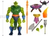A green, reptilian action figure with various accessories, including weapons and armor, displayed on a white background. A ruler graphic indicating measurements is present on the left side. Náhled obrázku produktu
