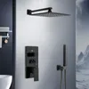 A modern black shower system with a square overhead shower head, a wall-mounted control panel with a digital display, and a handheld shower head, set against a light gray wall with a hint of a mountain landscape on the right. Náhled obrázku produktu