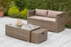 An outdoor patio set with a sofa and coffee table on a tiled surface, surrounded by greenery. Produktbild-Vorschau