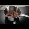 Chocolate melting in a saucepan on a stovetop. Voir les images du produit
