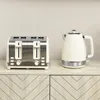 A cream-colored electric kettle and a cream and silver toaster sit side-by-side on a light wood cabinet. Produktbild-Vorschau