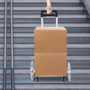 A hand is holding the handle of a wheeled cart with a cardboard box on it, as it is being moved up a set of stairs. Náhled obrázku produktu