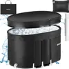 A black inflatable ice bath tub filled with ice cubes, with its lid partially open. Accessories like a carrying bag, a pillow, and a pump are displayed around it. Water splashes are visible on the left side. Náhled obrázku produktu