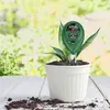 A three-way soil meter is inserted into a potted plant on a white wooden surface, with a blurred green background of foliage. Podgląd zdjęcia produktu