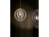 Two modern pendant lights with a circular, layered design hang against a dark, textured wall. Náhled obrázku produktu