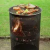 A black metal fire pit with a grill grate on top, cooking food outdoors on a grassy lawn. Produktbild-Vorschau