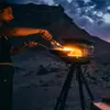 A woman is cooking outdoors at dusk with a portable pizza oven. Produktbild-Vorschau
