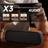A person is holding a smartphone behind a black portable Bluetooth speaker. Produktbild-Vorschau