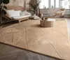 A cozy living room scene featuring a beige rug with a geometric pattern, a rattan sofa, and a round coffee table. Anteprima dell’immagine prodotto