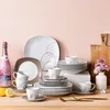 A collection of dinnerware and a bottle of pink champagne are arranged on a wooden surface against a light pink background. Náhled obrázku produktu