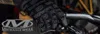 A close-up shot of a person's hands wearing black gloves and holding onto the handlebars of a bicycle. Produktbild-Vorschau
