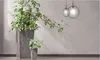 Two potted plants in gray planters against a textured gray wall with two circular pendant lights hanging above. Voir les images du produit