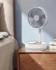 A portable fan is placed on a wooden nightstand next to a bed. Náhled obrázku produktu