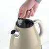 A hand is inserting a filter into a cream-colored electric kettle. Anteprima dell’immagine prodotto