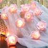 A string of pink rose-shaped LED lights is draped over a white sheer fabric, with a woven basket in the background. Produktbild-Vorschau