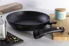 A black frying pan with a detachable handle is shown on a countertop, with some spices and a jar in the background. Anteprima dell’immagine prodotto